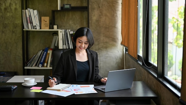 A businesswoman focuses on her work reviewing marketing reports at her desk