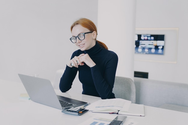 Businesswoman in glasses has online business video conference and smiling at camera