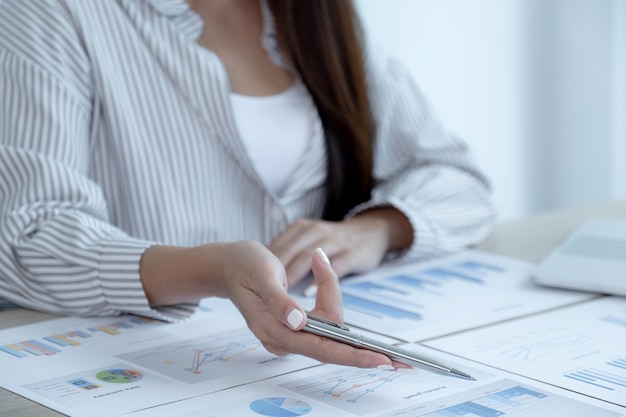 Businesswoman hand holding pen and analysis the chart with laptop at the office for setting challenging business goals And planning to achieve the new target.