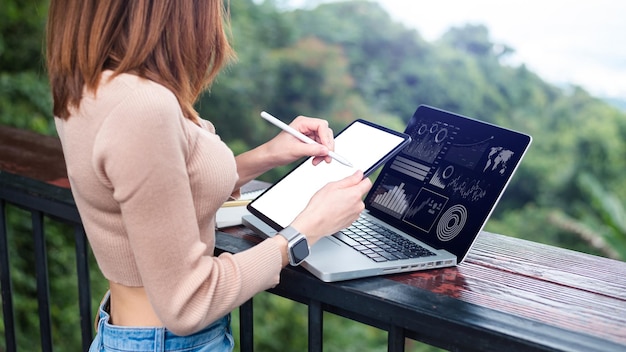 Businesswoman hand working with laptop computer and tablet in outdoor office with virtual icon diagram