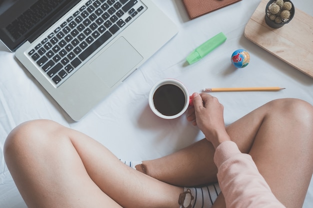 Businesswoman hands holding cups of coffee and using laptop