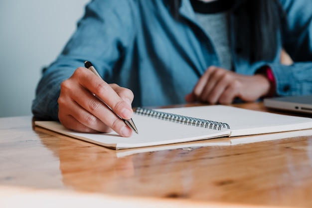 Businesswoman hands with pen writing notebook