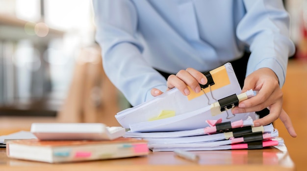 Businesswoman hands working in Stacks of paper files for searching and checking unfinished document achieves on folders papersx9