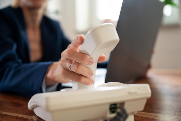 Businesswoman hanging or picking up a white landline phone handset