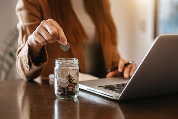 Businesswoman holding coins putting in glass with using smartphone and calculator to calculate concept saving money for finance accounting