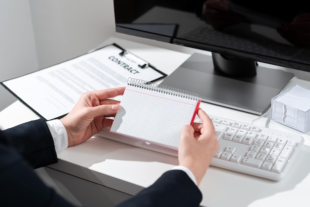 Businesswoman Holding Important Message Wtitten On Notebook On Desk With Computer Clipboard And Notes Crutial Information Presented On Notepad On Table With Keyboard And Pc