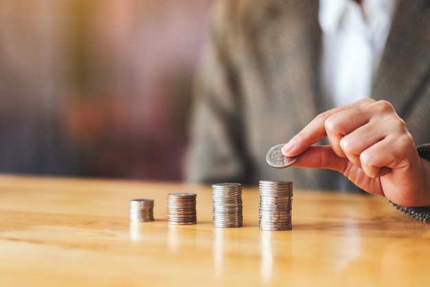 Businesswoman holding and stacking coins on the table for saving money concept