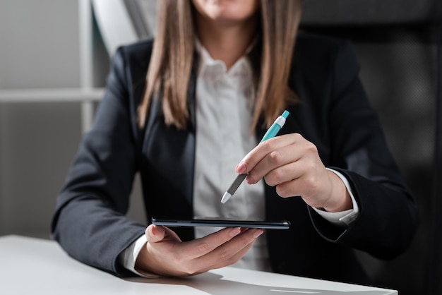 Businesswoman holding tablet in one hand and pointing on it with pen in hand sitting woman in