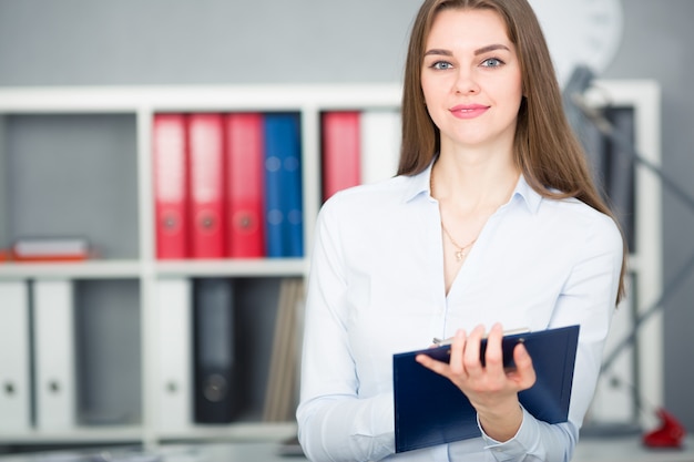 Businesswoman holding tablet and a pen on office background