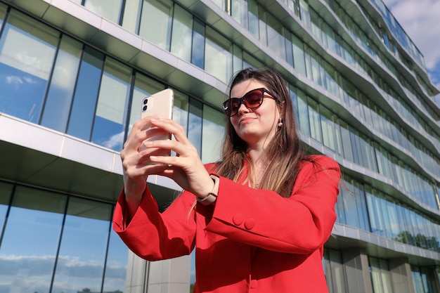 A businesswoman in a jacket talks on a video link on the street