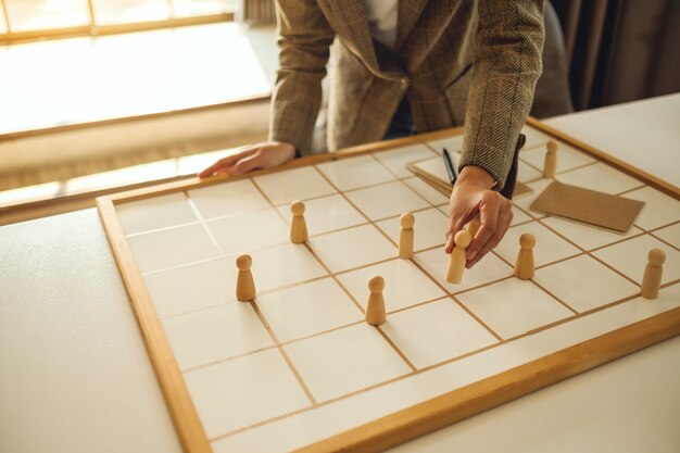 Businesswoman leader choosing wooden people from a group of employees on a planning board