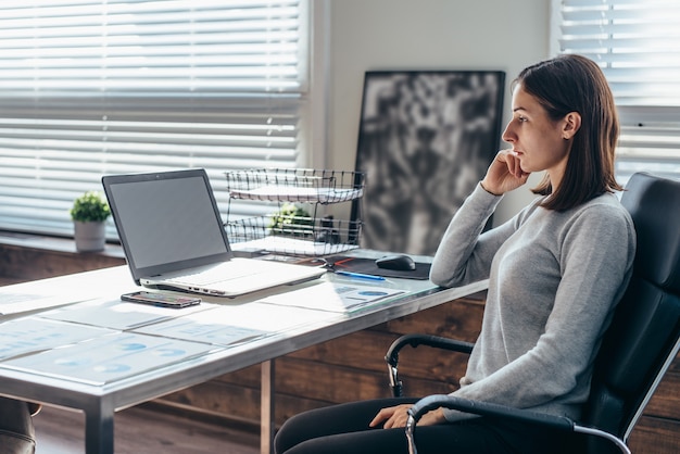 Businesswoman looking at laptop screen while working in office.