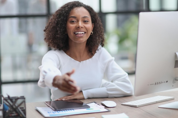 Businesswoman offering handshake standing with extended hand in modern office