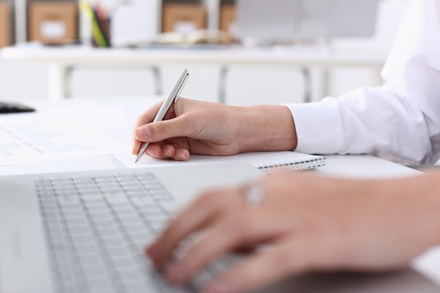 Businesswoman in the office holds her hand on the laptop makes financial analysis and calculation of expenses and incomes of the enterprise forms a report on the work done for the reporting period.