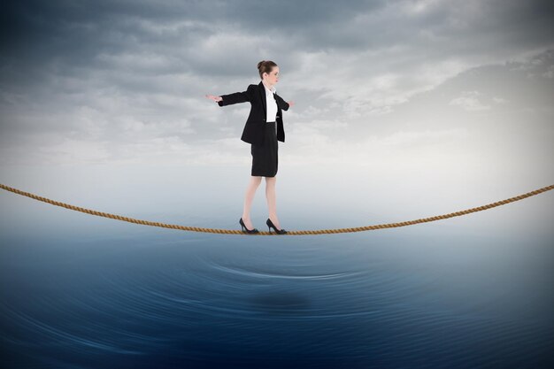 Photo businesswoman performing a balancing act against cloudy sky over ocean