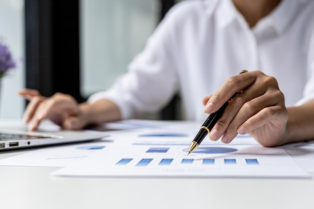 Businesswoman pointing to a chart document showing company financial information, she sits in her private office, a document showing company financial information in chart form. Financial concepts