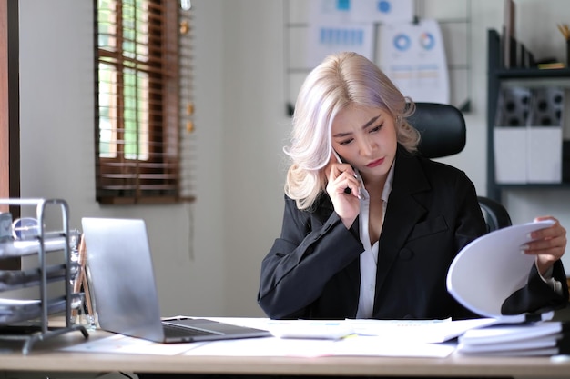 Businesswoman reading document while speaking on the phone at office