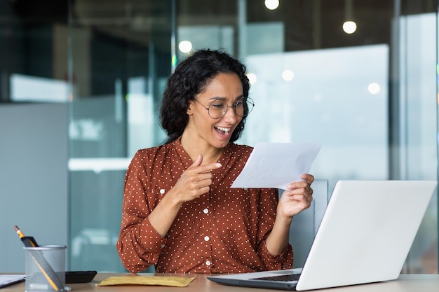 Businesswoman received happy news letter from bank hispanic woman with curly hair and glasses works