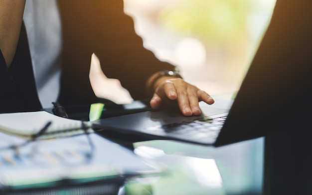 Businesswoman's hand touching on laptop computer touchpad while working in office