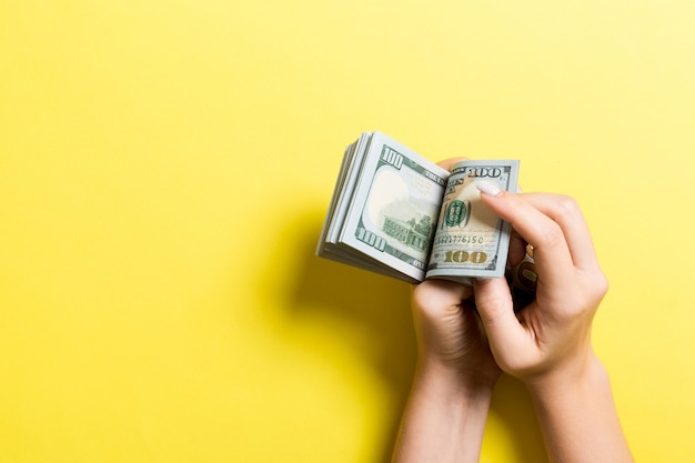 Businesswoman's hands counting one hundred dollar bills on colorful . Salary and wage   copyspace. Top view Investment 