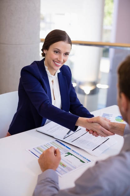 Businesswoman shaking hands with colleague at desk