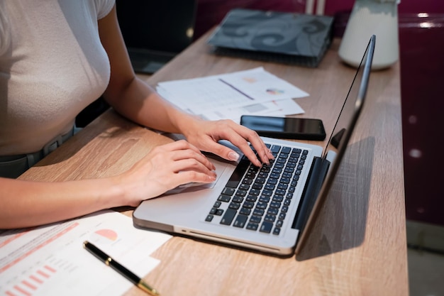 Businesswoman sitting at a desk business woman's hands resting on laptop computer keyboard