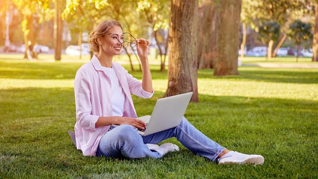 Businesswoman sitting grass summer park using laptop Business person working remote Outdoor