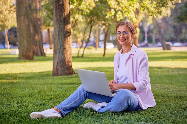 Businesswoman sitting grass summer park using laptop Business person working remote