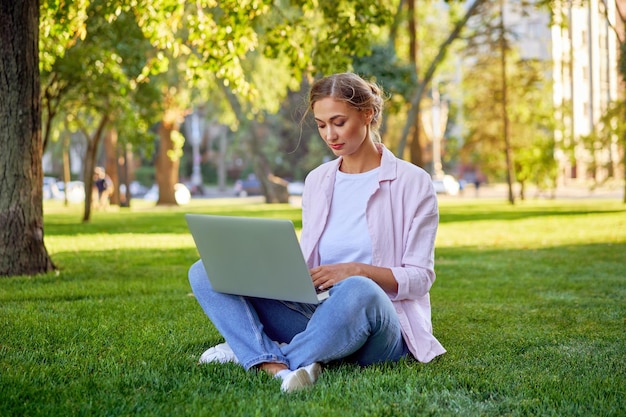 Businesswoman sitting grass summer park using laptop Business persone working remote Outdoors