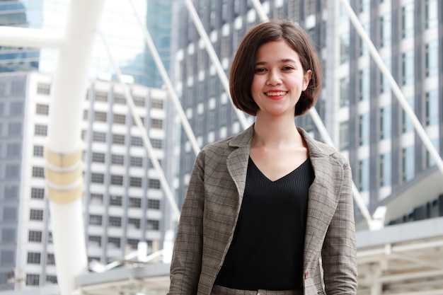 Businesswoman smiling in city and building in background.