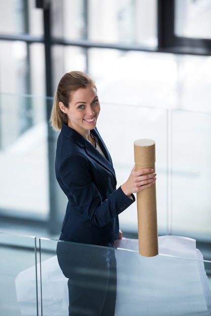 Businesswoman standing at office corridor with chart holder