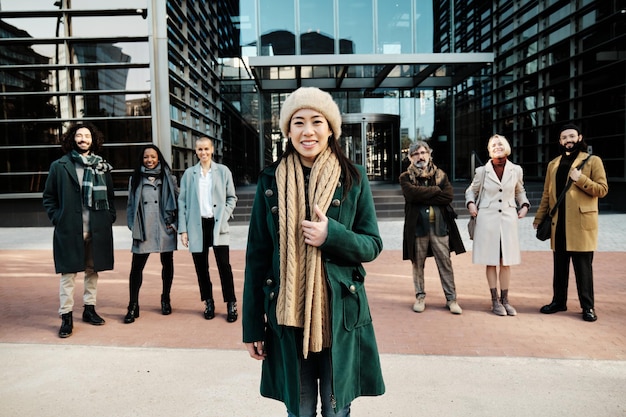 Businesswoman standing out from a diverse group of business people while posing together outside the office building.