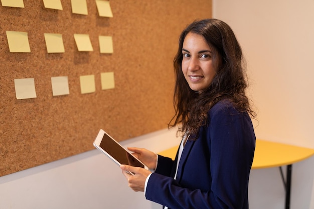 Businesswoman standing with digital tablet and looking at camera