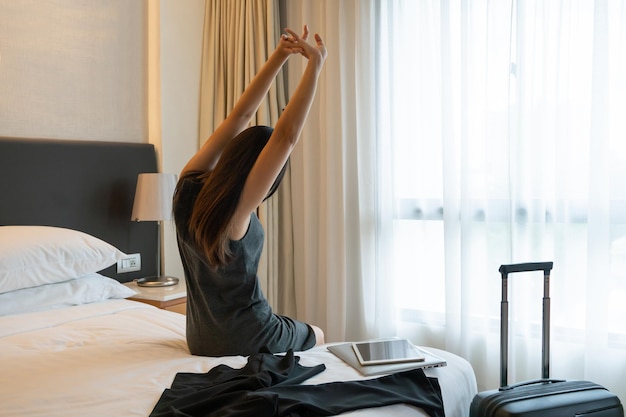 Businesswoman stretching on a bed in hotel room. Woman take a rest in bed Business trip concept