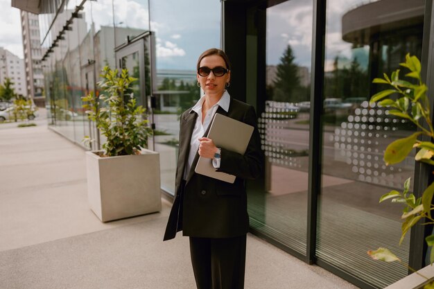 Businesswoman in stylish suit outside modern office building showing professionalism and success