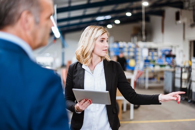 Businesswoman talking to business founder holding digital tablet