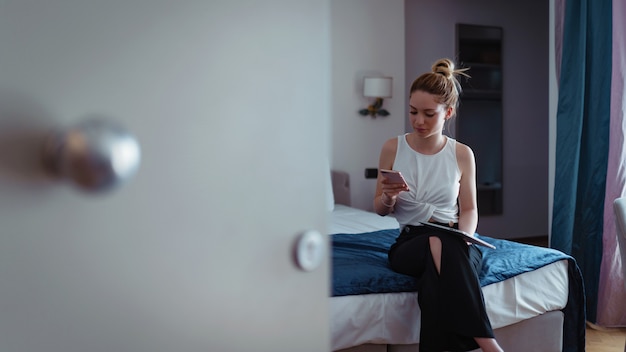 Businesswoman talking at the phone and working with tablet in hotel room.