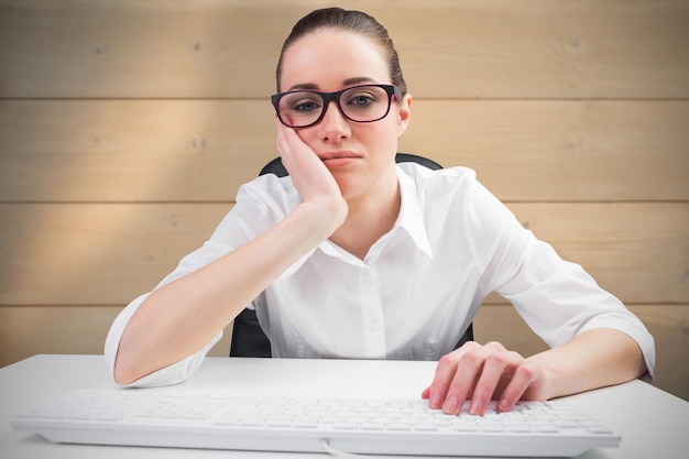 Businesswoman typing on a keyboard against bleached wooden planks background