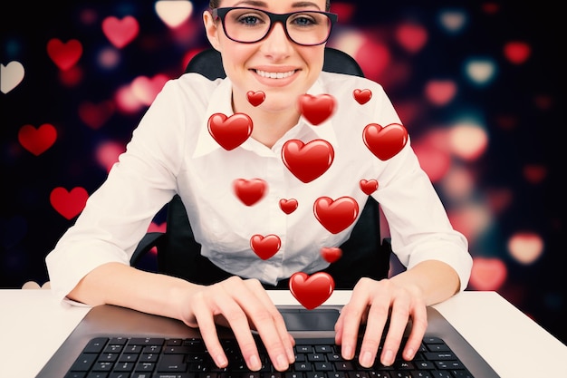 Businesswoman typing on a keyboard against valentines heart pattern