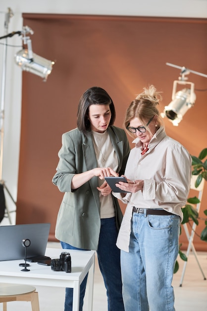 Businesswoman using digital tablet together with her colleague while they standing at office