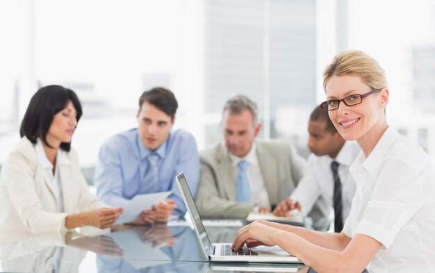 Businesswoman using her laptop during a meeting looking at camera