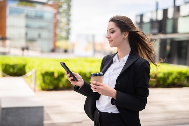 Businesswoman using her mobile phone while walking outdoor