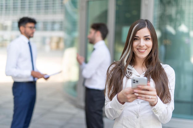 Businesswoman using her smartphone in front of her office