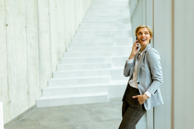 Businesswoman using mobile phone on modern office hallway