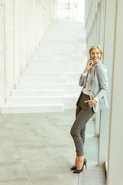 Businesswoman using mobile phone on modern office hallway