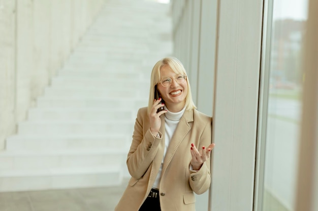 Businesswoman using mobile phone on modern office hallway