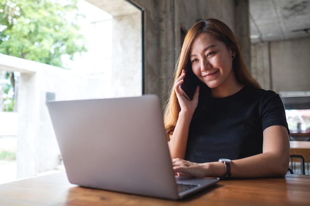 A businesswoman using mobile phone and working on laptop computer in office