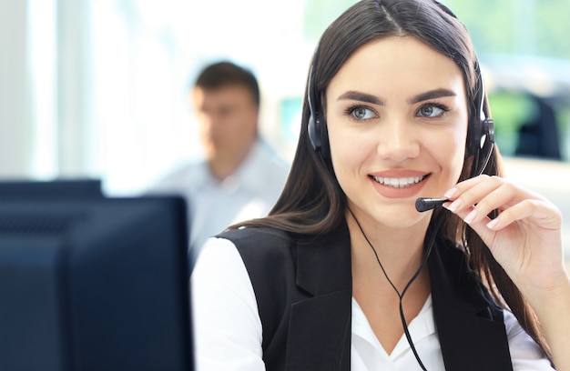 Businesswoman wearing microphone headset using computer in the office - operator, call center.