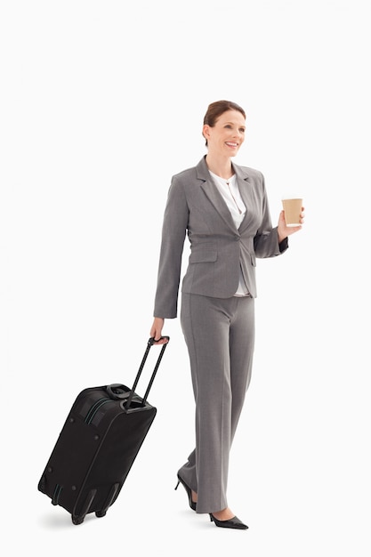 Businesswoman with coffee and suitcase