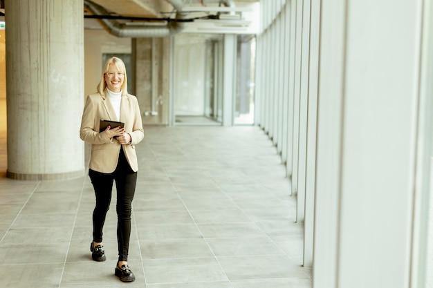 Businesswoman with digital tablet on modern office hallway